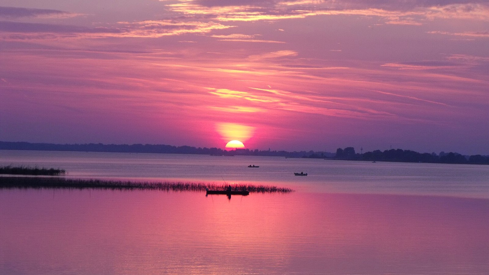 Abádszalók, naplemente a Tisza-tó partján, a vízen csónakokkal.