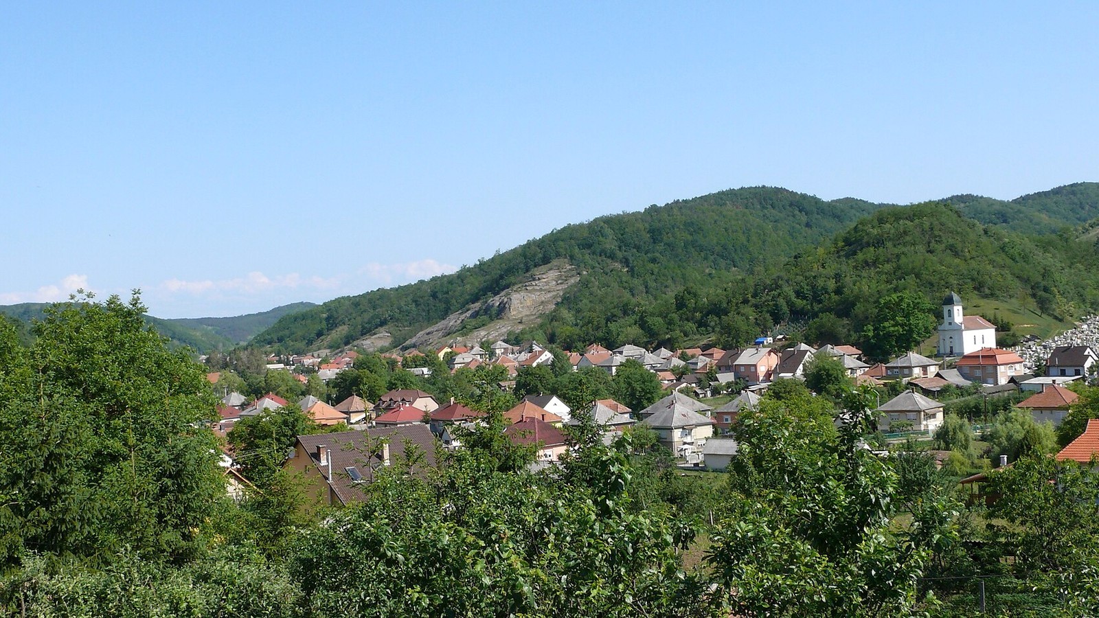Istenmezeje panorámája erdős dombokkal és házakkal.