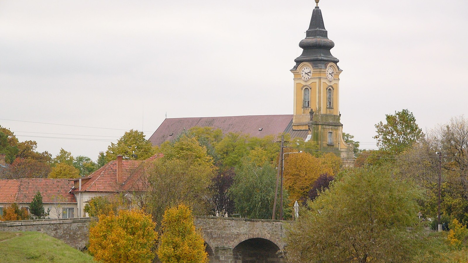 Jászdózsa őszi látképe a Mihály arkangyal-templom tornyával és a régi kőhíddal.