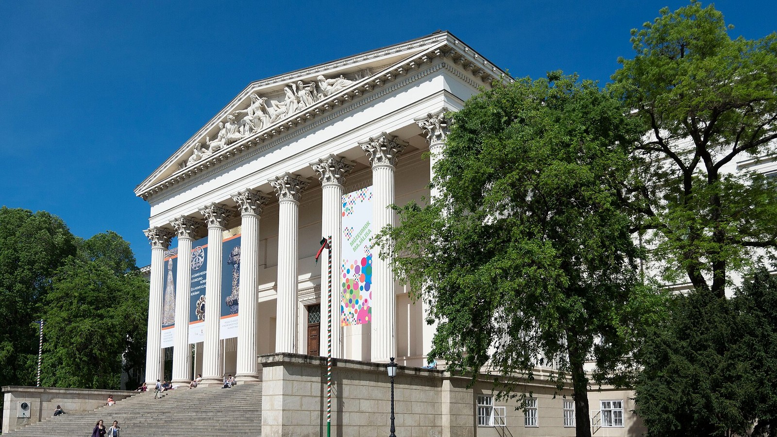 Józsefváros, a Magyar Nemzeti Múzeum klasszicista oszlopos főhomlokzata a lépcsősorral és a múzeumkert virágágyásaival.