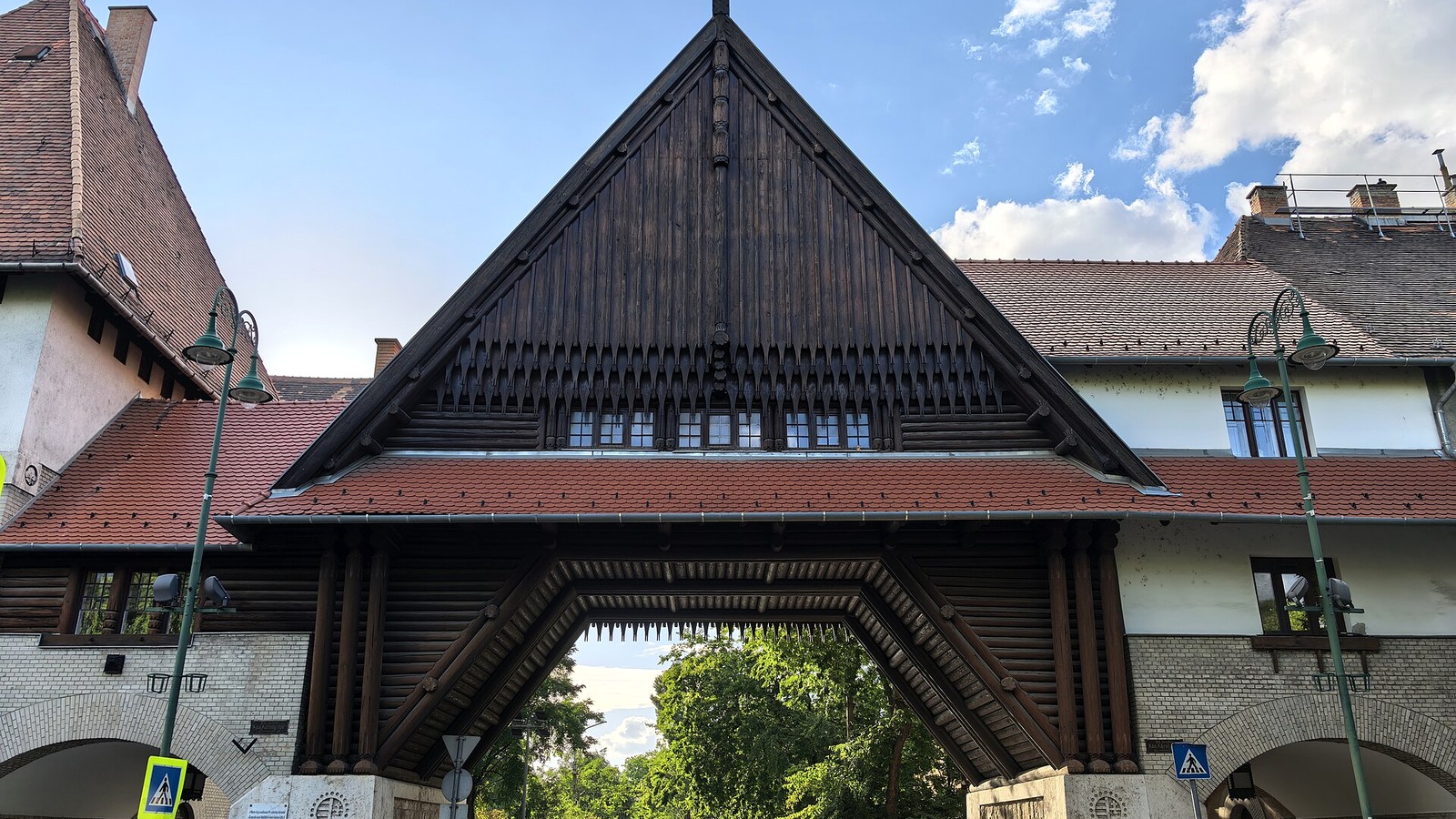 Kispest, a Wekerle-telep fa oromzatos Zrumeczky-kapuja a Kós Károly téren, alatta az átjáróval és a zöld utcával.