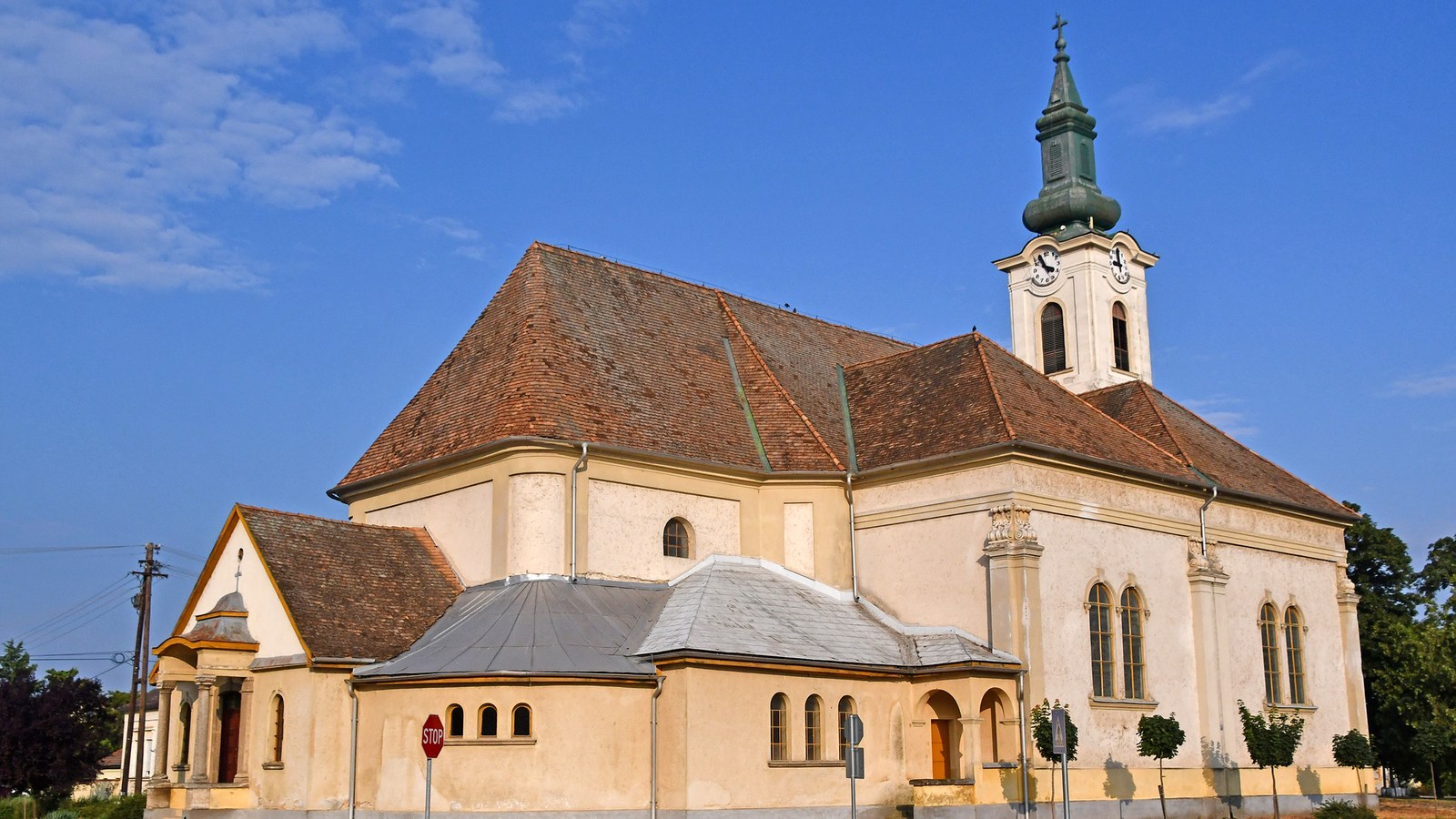 Madaras, az 1799-ben épült Nagyboldogasszony-templom sárga falai, barna cseréptetője és zöld sisakos, órás tornya.