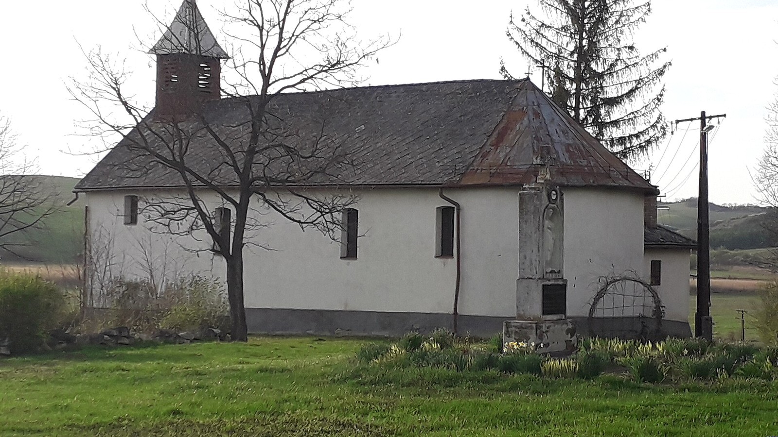 Terpes, a régi, fehérre meszelt templom fatoronnyal és zöld templomkerttel.