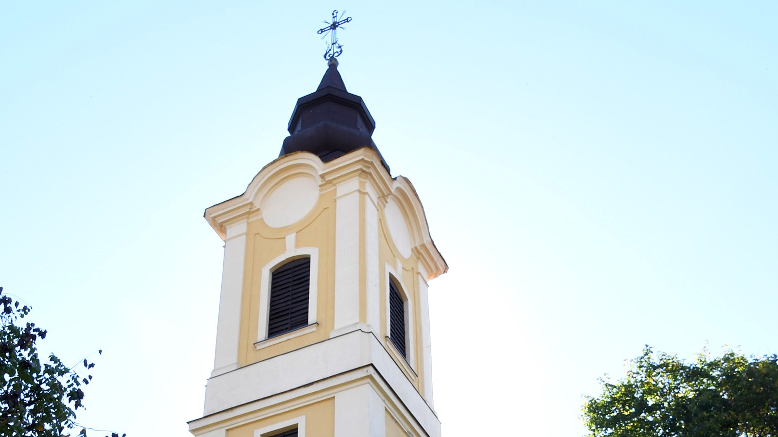 Tiszaörs, az 1783-ban épült római katolikus templom tornya és homlokzatának felső része, kék ég alatt.