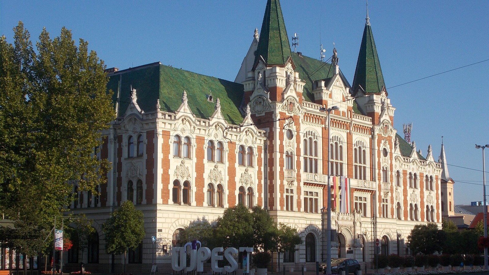 Újpest, a városháza zöld tetős, tornyos, vörös-fehér homlokzatú eklektikus épülete a Szent István tér felől.