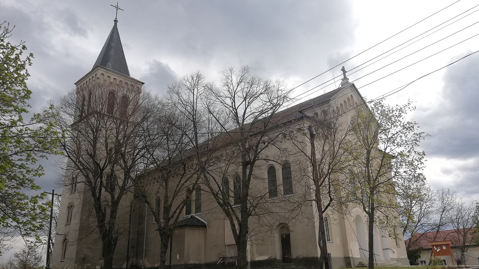 Újszász, a római katolikus templom a templomkert lombtalan fáival.